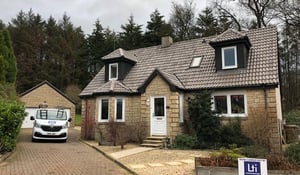 A skilled worker is inspecting a recently refurbished roof, examining the roof tiles for any signs of damage to ensure its integrity and longevity.